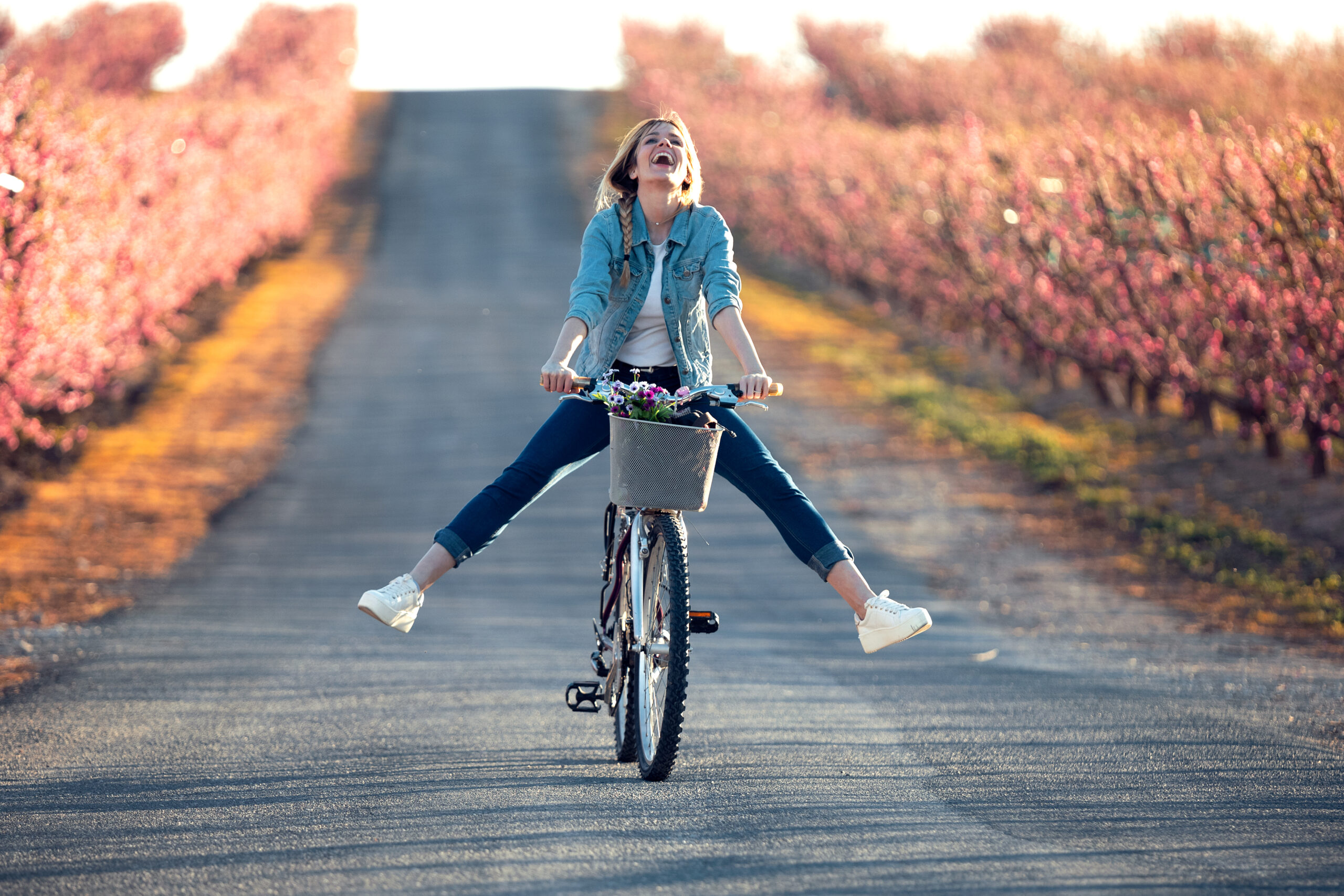 Pretty young woman with a vintage bike enjoying the time in cherry field in springtime