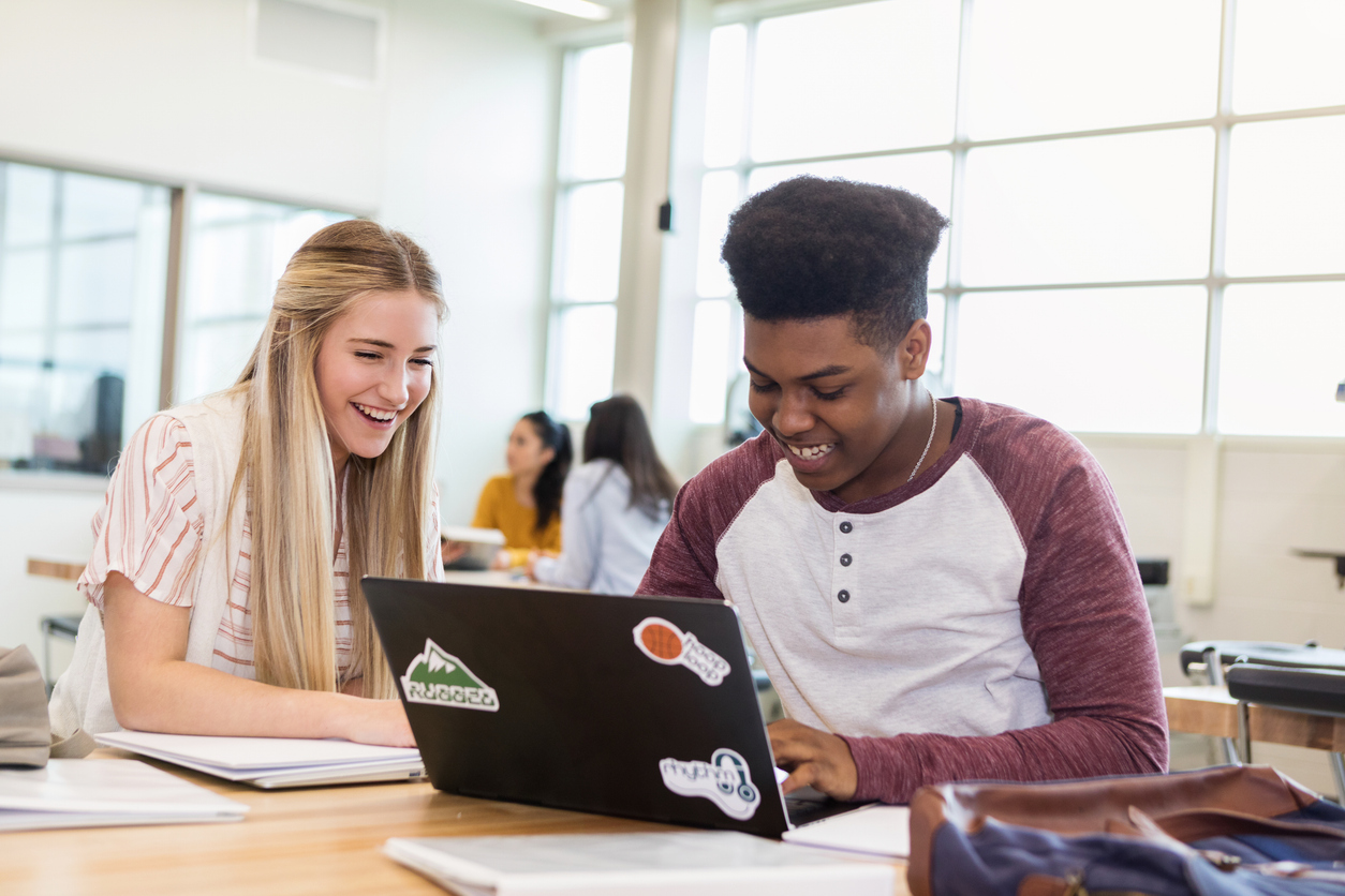 Diverse high school friends use laptop together